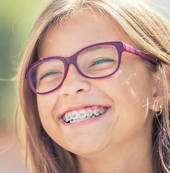 Smiling young girl with braces, receiving orthodontic care from Dr. Boris Kaltchev.
