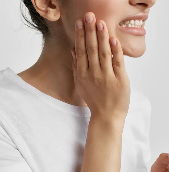 Close-up of a woman touching her jaw, indicating discomfort or pain in the temporomandibular joint (TMJ).