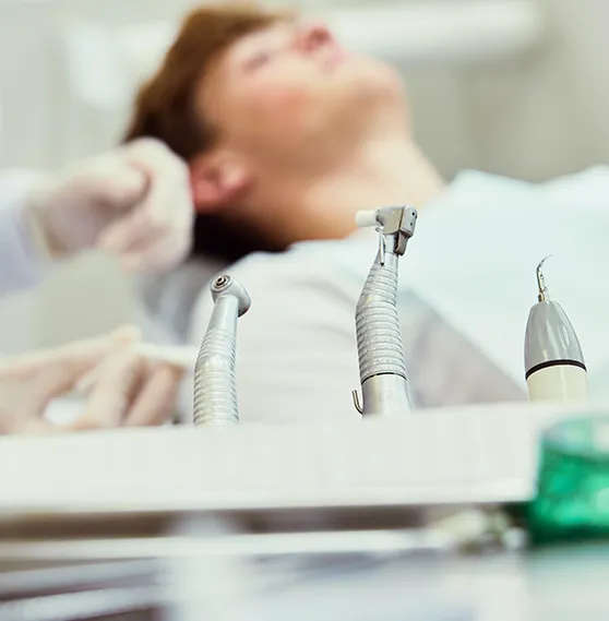 Close-up of dental tools with a patient in the background during treatment.